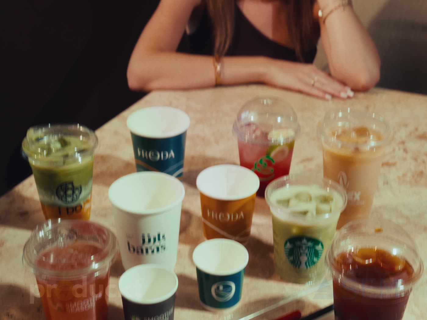 Printed paper and plastic cups for different café brands on a table in Erbil